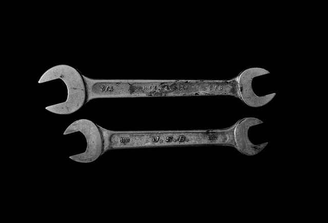 Two silver open wrenches on a black background